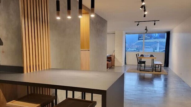 Una cocina moderna con una pared de acento de madera, iluminación colgante y vistas de la ciudad a través de ventanas amplias.