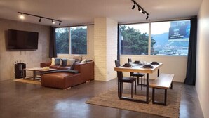 Una sala de estar moderna con un sofá, una mesa de comedor y un televisor montado en la pared.