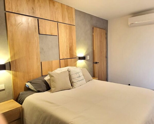 A bedroom with a bed, bedside tables, a wardrobe, and a wall-mounted light fixture.