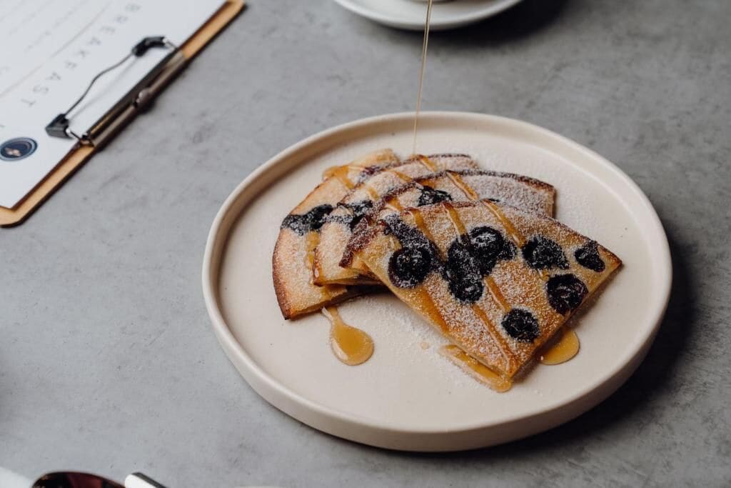 A plate of pancakes with blueberries and syrup.