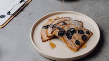 A plate of pancakes with blueberries and syrup.