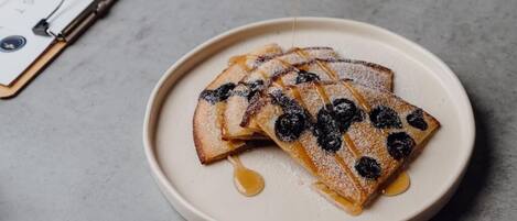 A plate of pancakes with blueberries and syrup.
