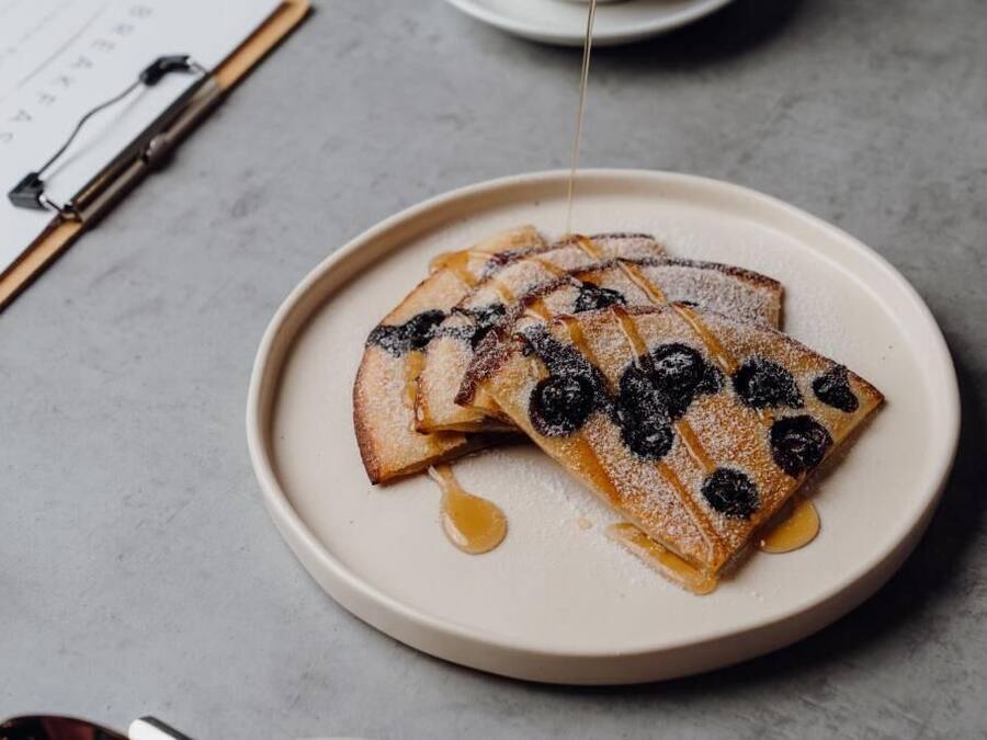 A plate of pancakes with blueberries and syrup.
