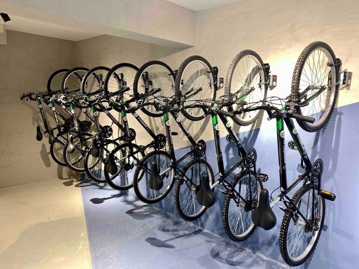 Eine Reihe Fahrräder ist an einer Wand in einem Zimmer mit hellem Boden und schlichten Wänden befestigt.