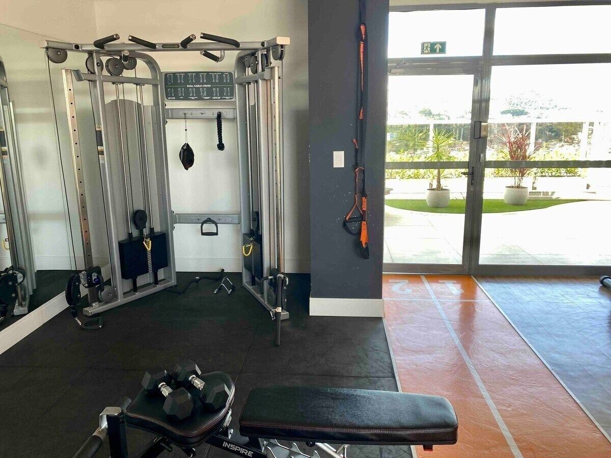 Un gimnasio con equipo de ejercicio, una banca y un amplio ventanal con vistas al exterior.