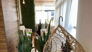 Un interno moderno con una poltrona sospesa, piante in vaso e una parete verde.