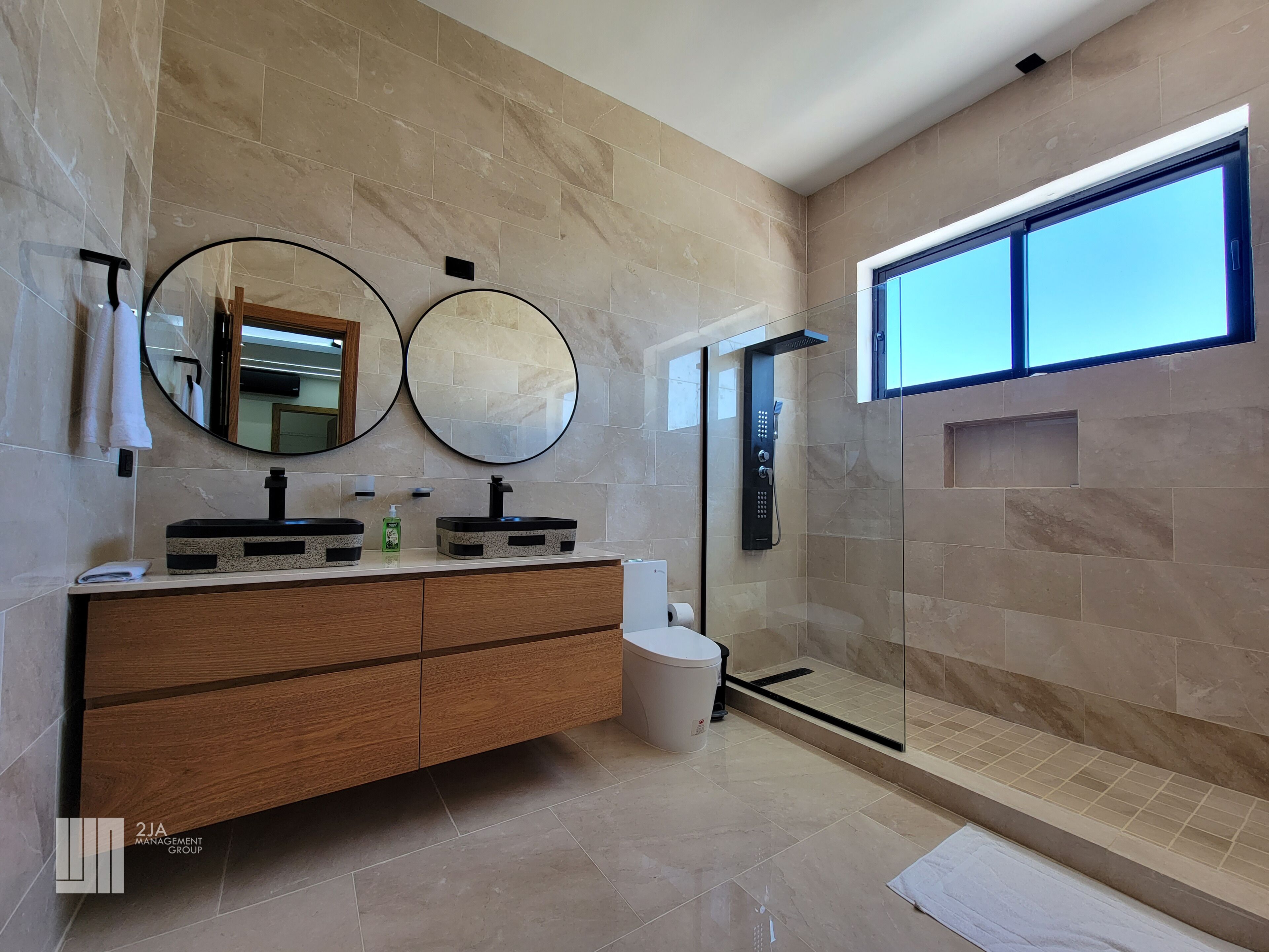 Une salle de bain moderne avec deux lavabos, un meuble-lavabo, une douche et une grande fenêtre.