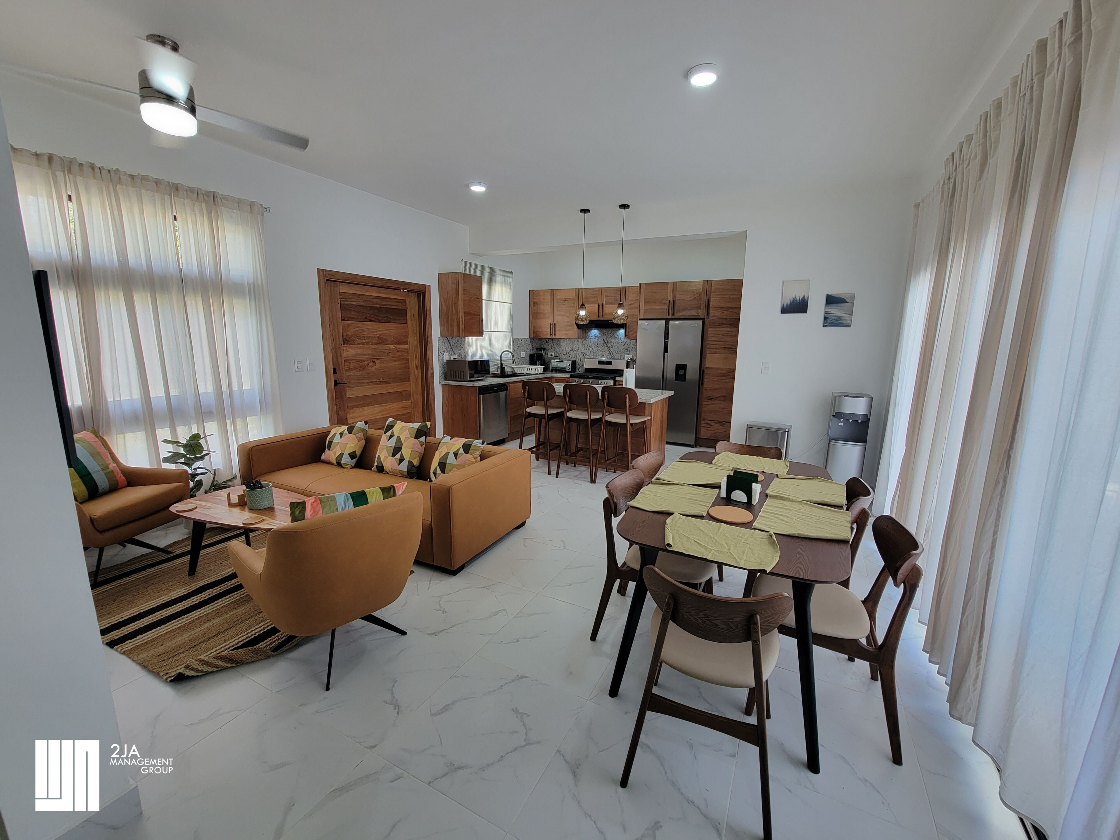 A modern living room with a sofa, coffee table, and dining area with chairs and a table.