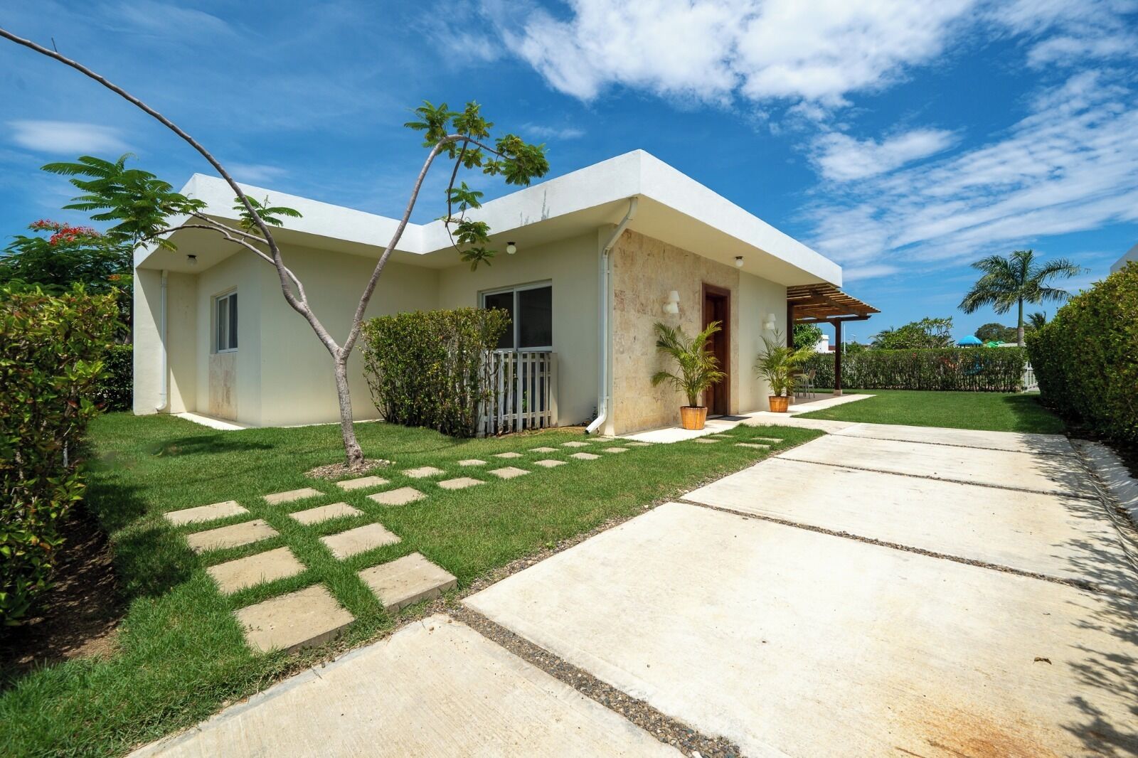 A single-story house with a front porch, a small lawn, and a concrete driveway.
