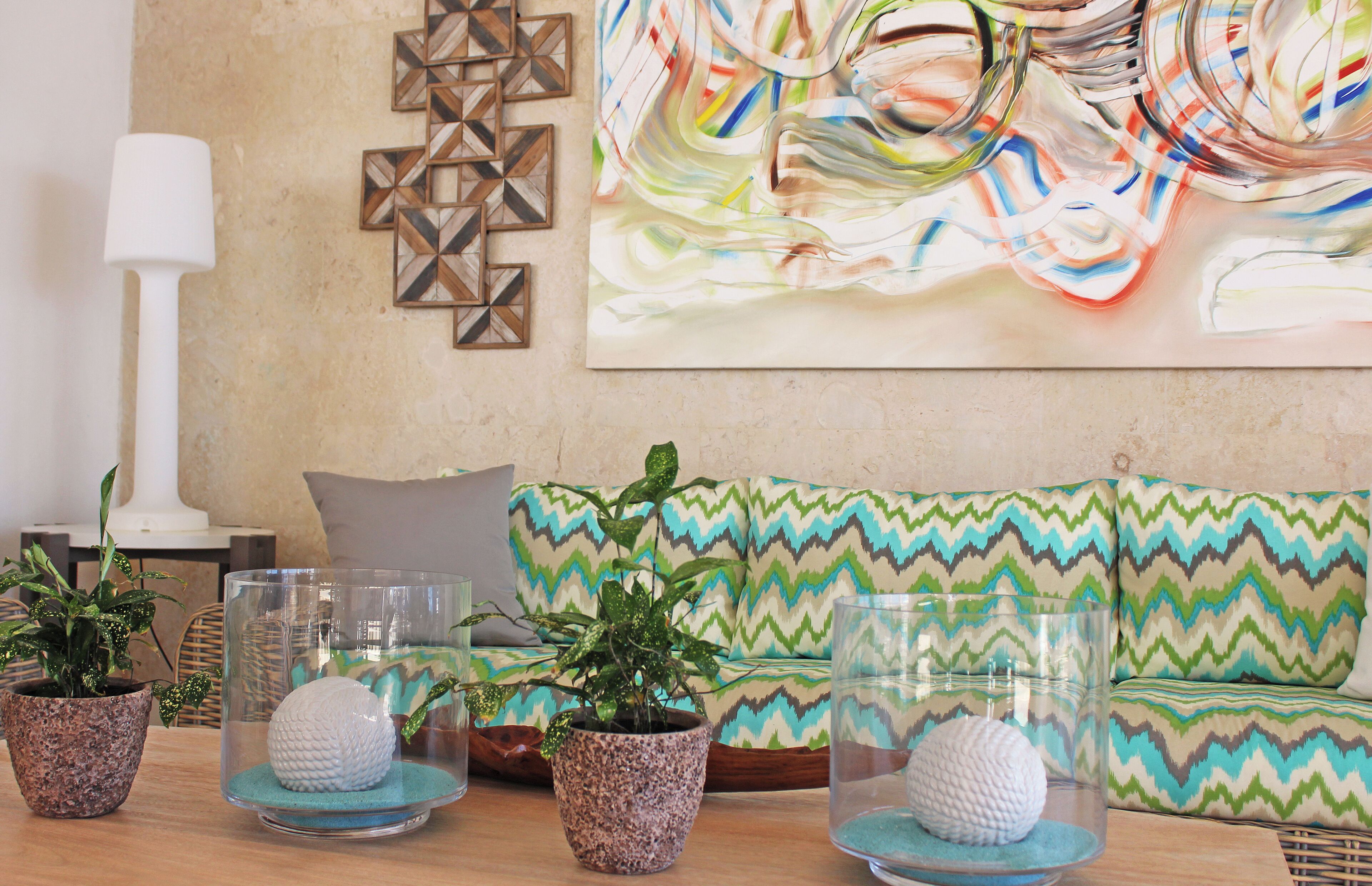 A living room with a sofa, decorative pillows, a wall art piece, and potted plants.