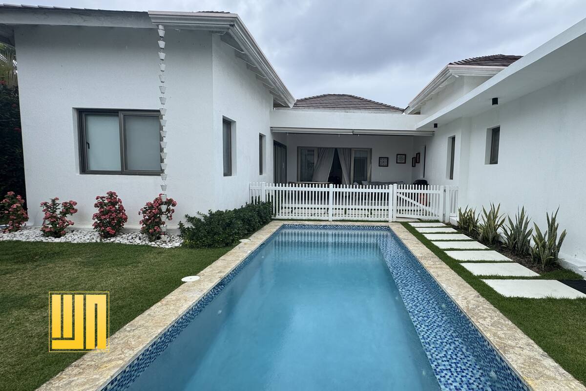 A modern house with a swimming pool, white exterior, and a covered patio area.