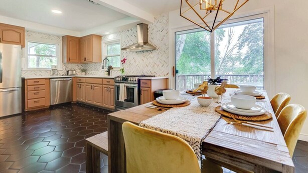 A modern kitchen with wooden cabinets, stainless steel appliances, and a large window providing natural light. - Midcentury Lake Home! (White Bear Lake)