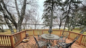 A wooden deck with a round table and chairs, surrounded by a wooden railing. - Midcentury Lake Home! (White Bear Lake)