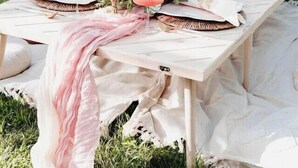 A picnic setup with a table set for two, featuring a pink cloth, a floral centerpiece, and a candle. - Midcentury Lake Home! (White Bear Lake)
