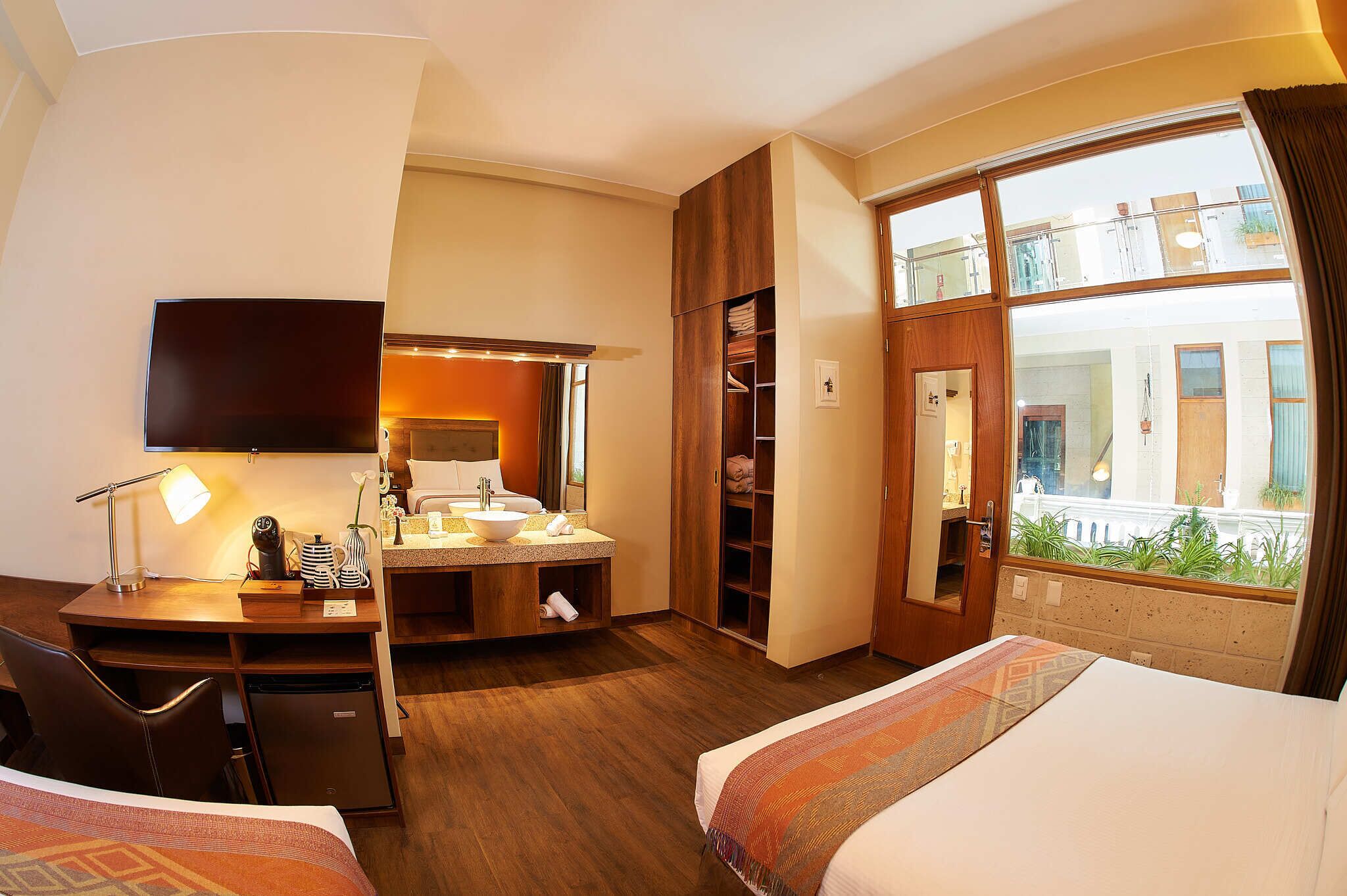 Habitación de hotel con cama, escritorio y un ventanal con vistas al exterior.