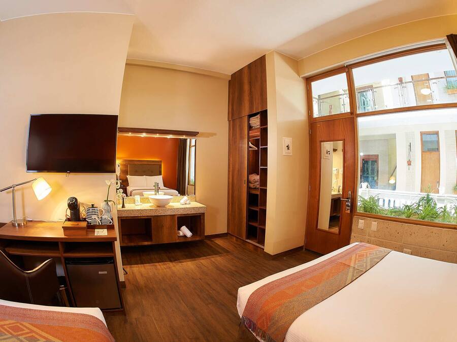 Habitación de hotel con cama, escritorio y un ventanal con vistas al exterior.