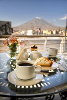 A table with a cup of coffee, a slice of pie, a vase with flowers, and a teapot.
