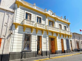 A historic building with ornate balconies, large wooden doors, and a flag.