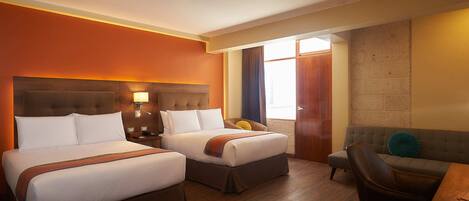 Habitación de hotel con dos camas, un sofá, un escritorio y una ventana con cortinas.