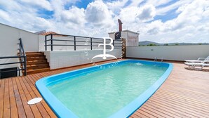 A rooftop swimming pool with a wooden deck, a metal railing, and a view of the sky and distant landscape. - Vista mar 2 suítes e piscina exterior (Florianópolis)