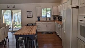 A modern kitchen with white cabinets, a wooden dining table, and a built-in oven. - 5 Bdrm, Amazing Sunsets, deck, flat yard, dock, fish, beach, kayaks... (Sparta)