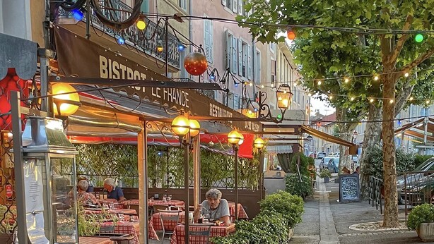 Ulkoterassi, jossa on pöytiä ja tuoleja, katulamppu ja kyltti, jossa lukee: ”BISTROT LE FRANCE”.