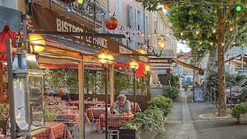 An outdoor café with tables and chairs, a street lamp, and a sign for 'BISTROT LE FRANCE'.