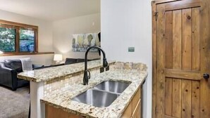 Una cocina con encimeras de granito, pileta doble y puerta de madera.