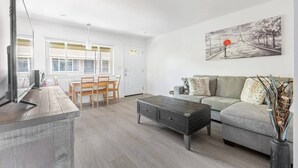 A modern living room with a grey sofa, a coffee table, and a painting on the wall. - Comfy 2BR Apt w/ AC/Washer/Dryer/EV - in Sunnyvale (Sunnyvale)