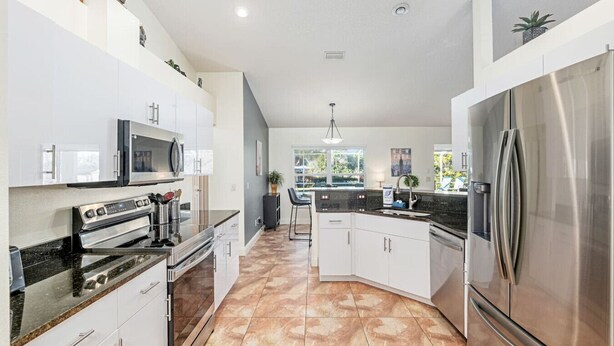 A modern kitchen with white cabinets, stainless steel appliances, and a large island. - Inverness Poolside Oasis 3 Bedroom (Inverness)