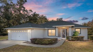 A single-story house with a garage, a front door, and a small front yard with bushes. - Inverness Poolside Oasis 3 Bedroom (Inverness)