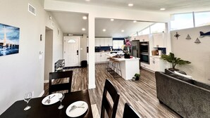 Une cuisine moderne avec des meubles blancs, un îlot central et un coin repas avec une table dressée pour deux personnes.
