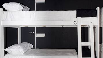 Una cama litera con dos niveles, identificados con las letras C y D, en una habitación con paredes oscuras y un cartel en la pared.