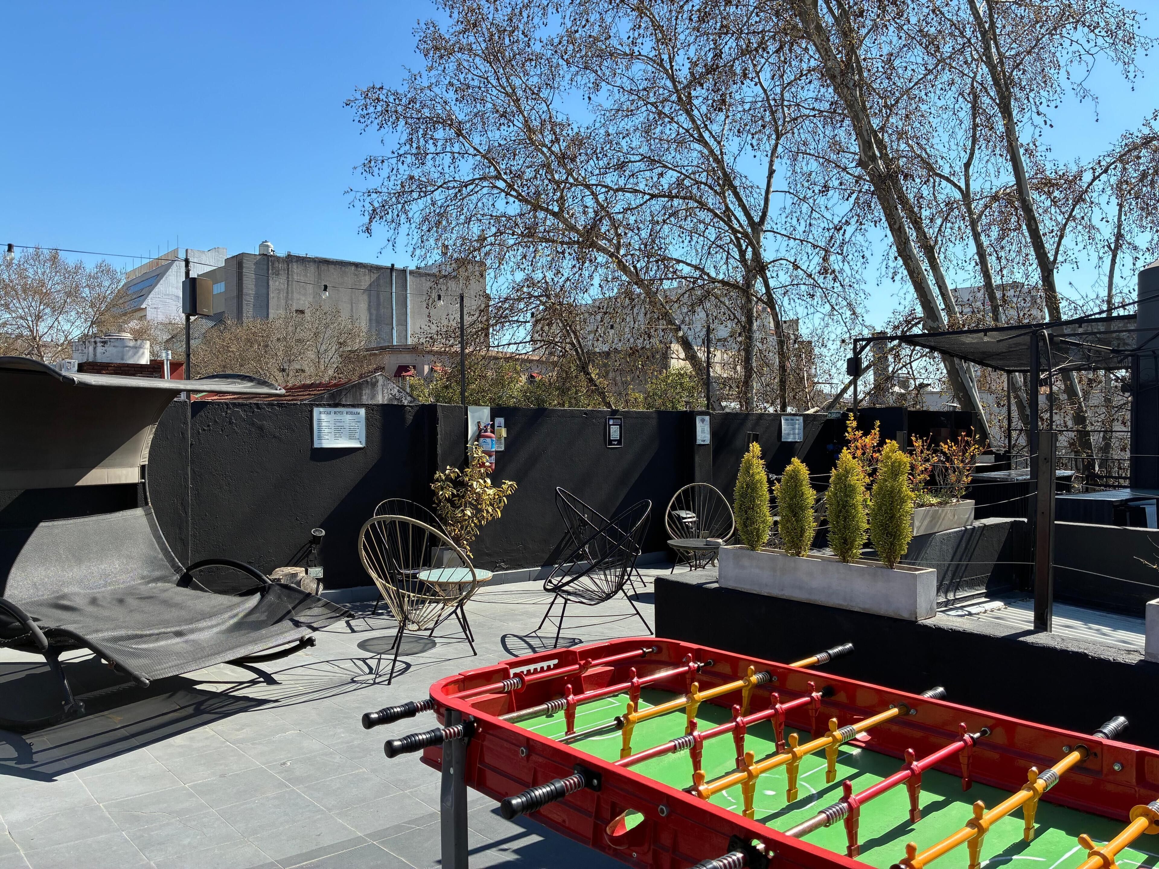 Terraza en la azotea con mesa de fútbol de mesa, mobiliario exterior y vista panorámica de la ciudad.