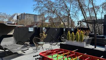 Terraza en la azotea con mesa de fútbol de mesa, mobiliario exterior y vista panorámica de la ciudad.