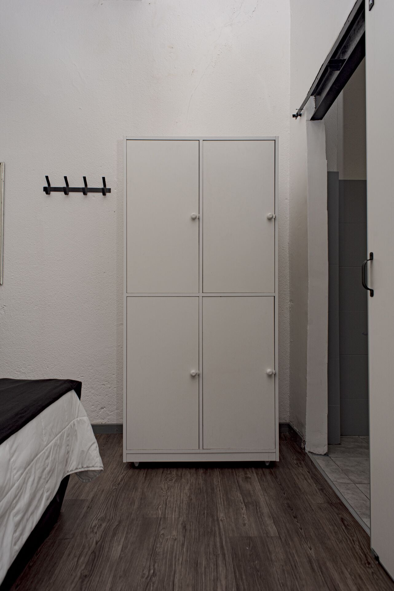 A bedroom with a bed, a wardrobe, and a door leading to a bathroom.