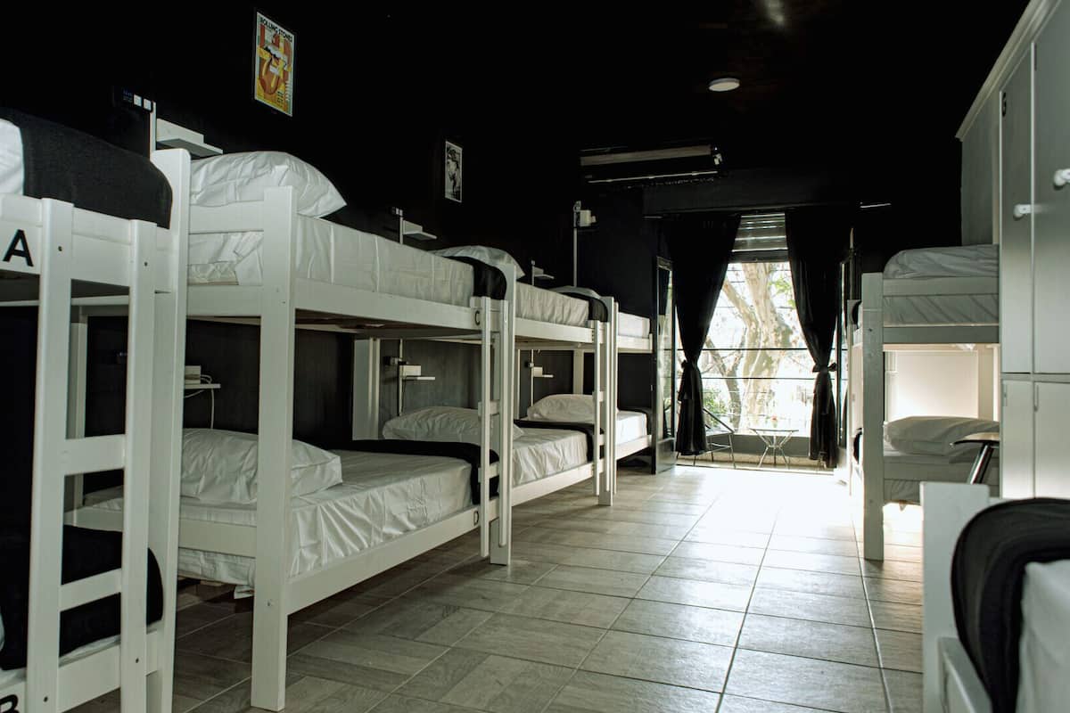 Un dormitorio con literas, suelo de baldosas y una ventana con cortinas.