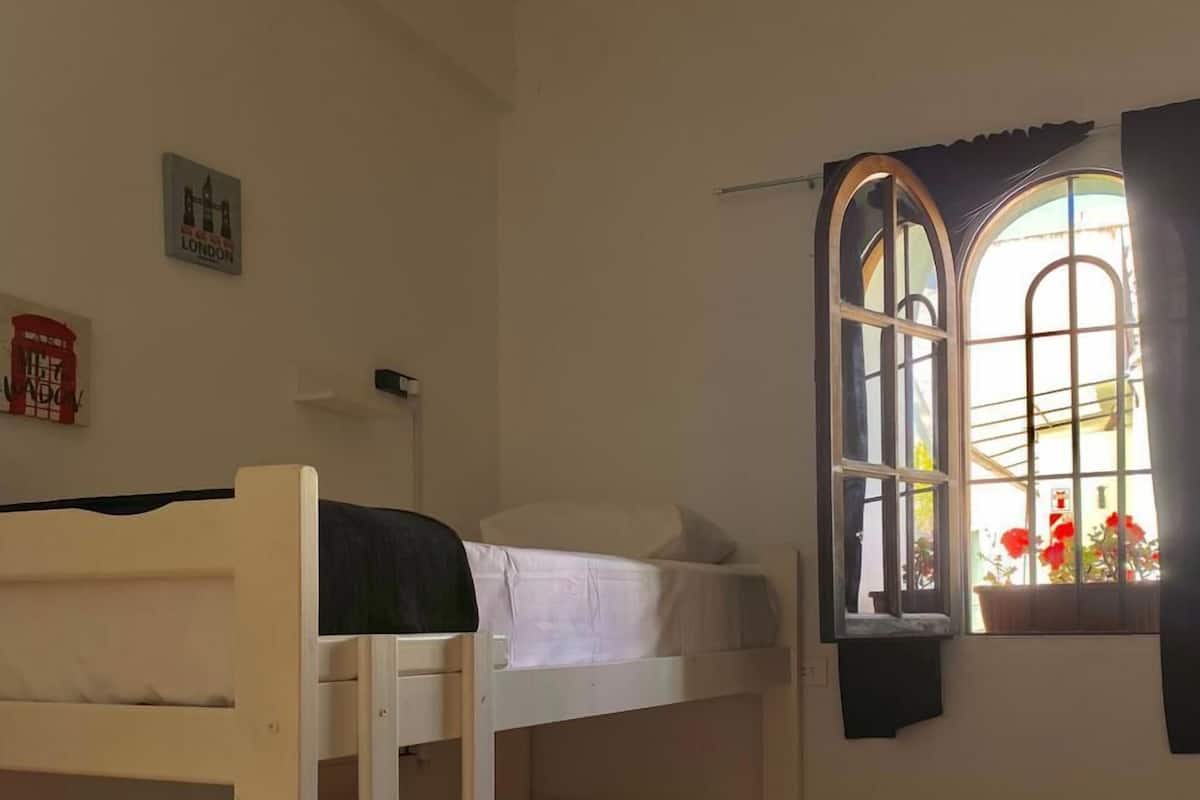 Habitación con literas, una ventana y una silla roja.