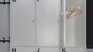 A white storage unit with compartments labeled G, H, I, J, and K. - PH Palermo Hostel (Buenos Aires)