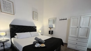 A hotel room with a black headboard, white bedding, a tray with breakfast items, a mirror, and a wardrobe. - PH Palermo Hostel (Buenos Aires)
