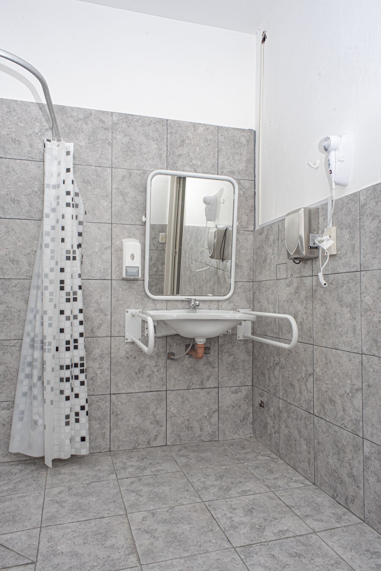 Een badkamer met een douche, een wastafel en een spiegel.