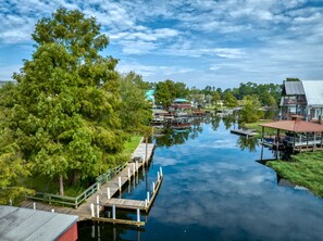 A riverside view with docked boats, a wooden pier, and a large tree.