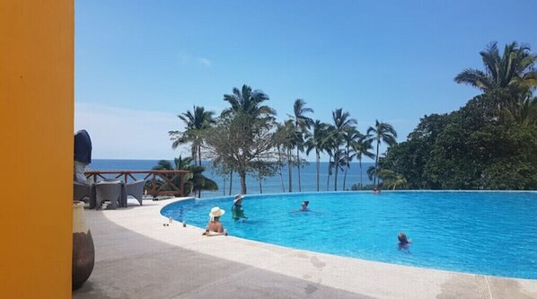 Relax by the ocean with a refreshing dip in the pool surrounded by palm trees and comfortable lounge chairs.