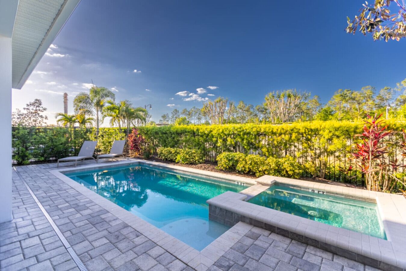 A rectangular swimming pool with two separate sections, surrounded by a paved deck.