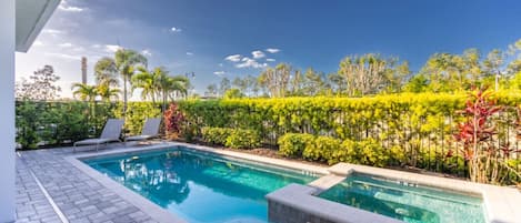 A rectangular swimming pool with two separate sections, surrounded by a paved deck.
