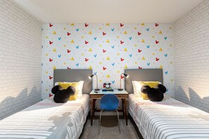 A room with two beds, a desk, and a chair.