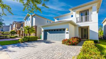 A modern two-story house with a garage, paved driveway, and well-maintained landscaping.