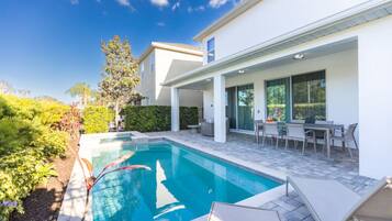 A modern house with a swimming pool, outdoor seating, and a well-maintained garden.