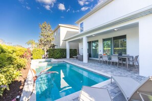 A modern house with a swimming pool, outdoor seating, and a well-maintained garden.