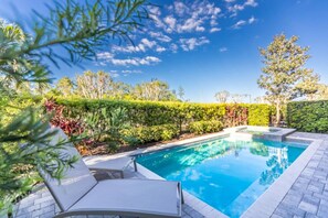A rectangular swimming pool with a tiled deck, surrounded by lush greenery and trees. - Amazing 5br House w/ Pool & Perfect Location! (Kissimmee)